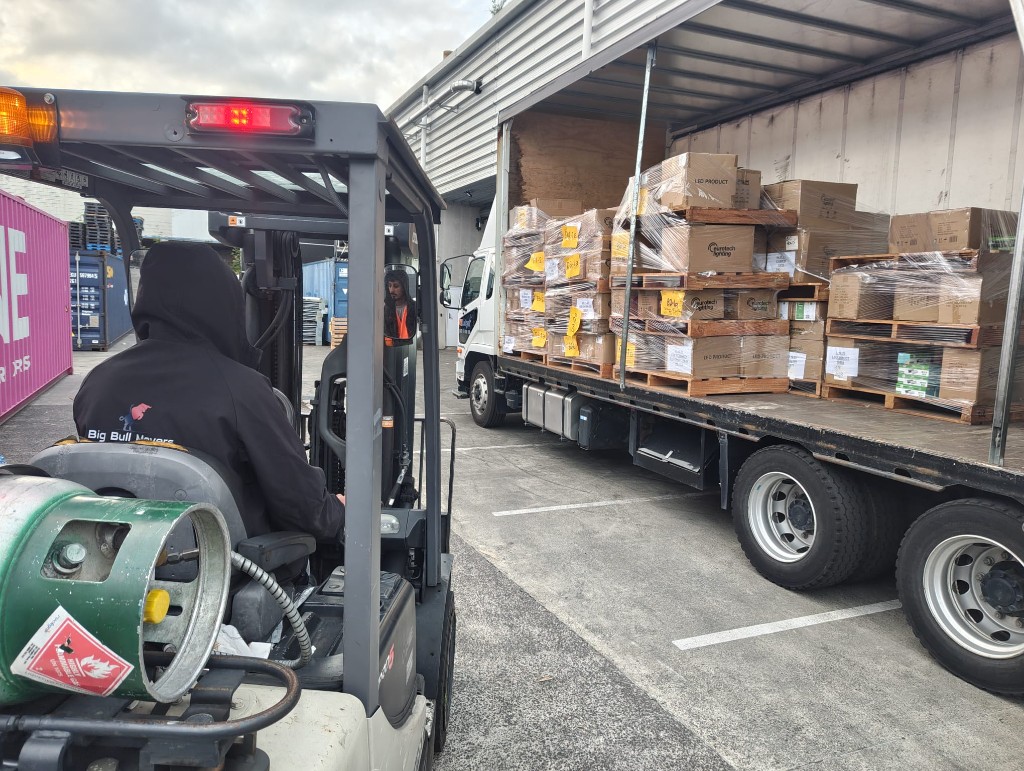 Commercial warehouse move Auckland – BigBull Commercial movers using a forklift to load wrapped pallets onto a moving truck
